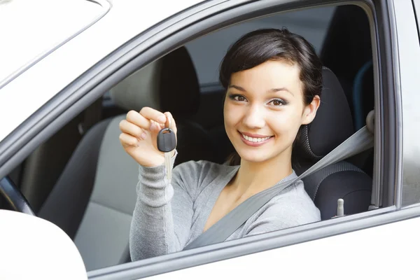 Pretty girl in a car showing the key — Stockfoto
