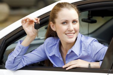 Pretty girl in a car showing the key