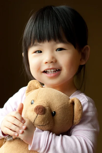 Criança sorridente com um urso de pelúcia — Fotografia de Stock