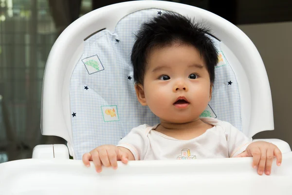 Pequeno bebê senta-se em uma cadeira alta — Fotografia de Stock