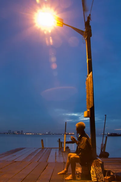 Lonely old man under a lamp pole