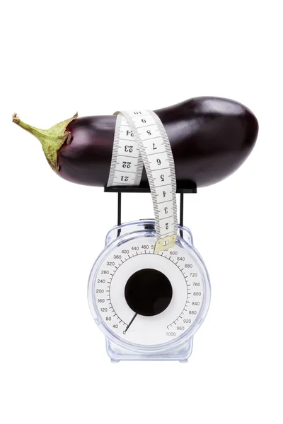 Баклажан с измерительной лентой на кухонном весе — стоковое фото