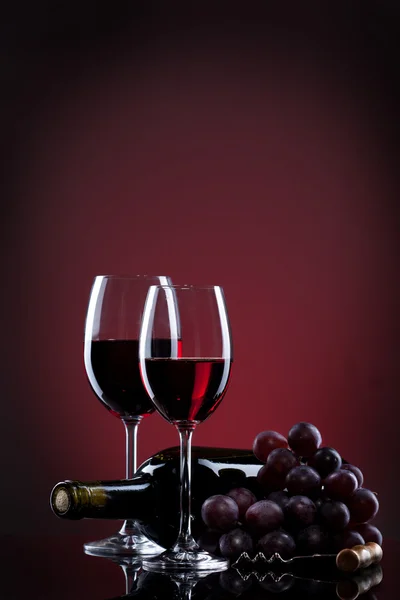 Vino en copas con uva y botella sobre rojo — Foto de Stock