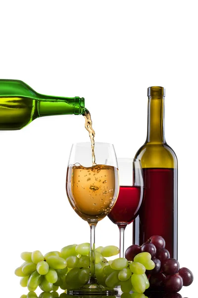 Vinho branco derramando em vidro com uva e garrafas isoladas — Fotografia de Stock