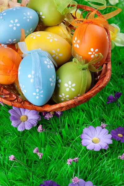 Color easter eggs in basket on the green grass — Stock Photo, Image
