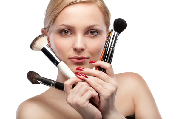 Mujer joven con cepillos de maquillaje aislados en blanco —  Fotos de Stock