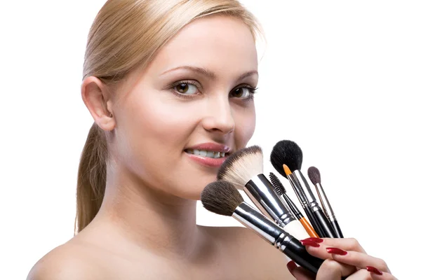 Jovem mulher sorridente com maquiagem escovas isoladas em branco — Fotografia de Stock