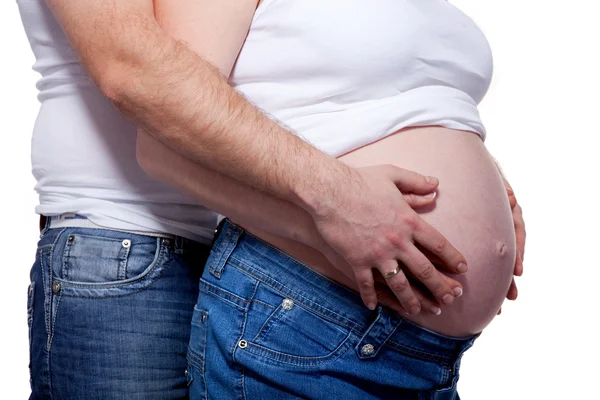 Мужские и женские руки над беременным животом на белом — стоковое фото