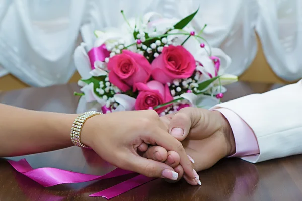 Handen van de pasgetrouwden en bruids boeket — Stockfoto