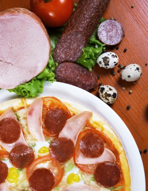 Pizza with salami, ham, edd and tomato clipart