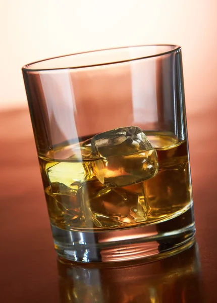 Whiskey with ice cubes on red — Stock Photo, Image
