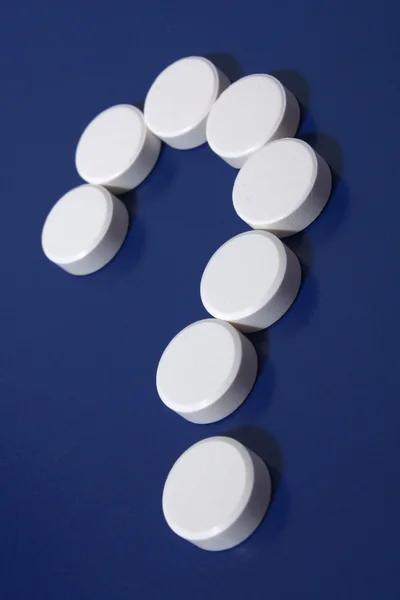 Fragezeichen hinter weißen Tabletten — Stockfoto