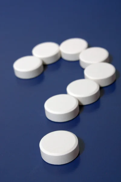 Fragezeichen hinter weißen Tabletten — Stockfoto