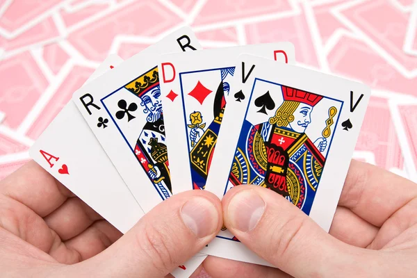 Mãos segurando quatro cartas de jogar. — Fotografia de Stock