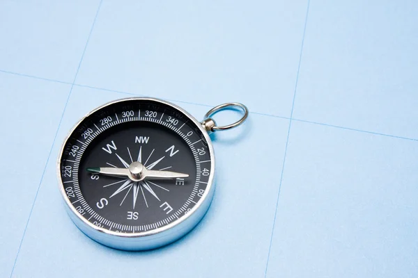 Black compass on blue paper background. — Stock Photo, Image