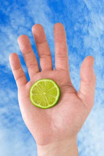 Hand with lemon on sky background. — Stock Photo, Image