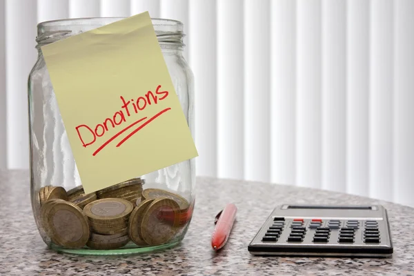 Jar voor donaties, pen en rekenmachine. — Stockfoto