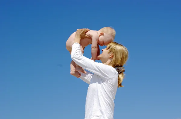 Boldog anya és a baba játszani a kék ég háttér — Stock Fotó