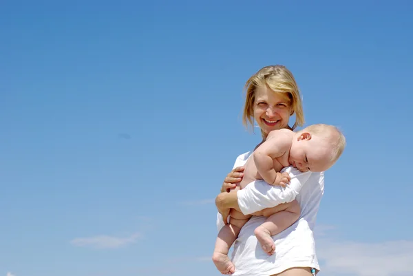 快乐妈妈和宝宝在蓝蓝的天空背景上播放 — 图库照片
