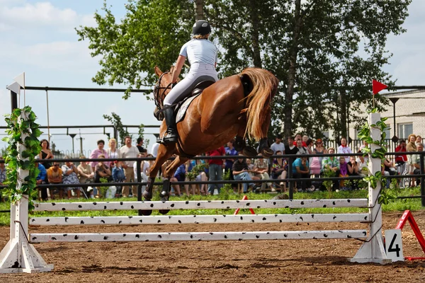 Tävlingar på concours - kvinnan hoppar igenom en barriär — Stockfoto