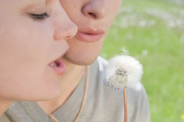 Girl and man are blowing on white dandelion — Stock Photo, Image