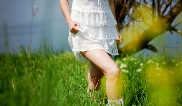 Девушка в белом платье ходит по зеленому полю — стоковое фото