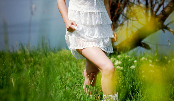 Girl in white dress walking in the green field
