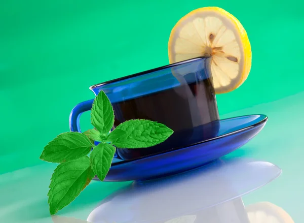 Nice cup of tea and mint on green background — Stock Photo, Image