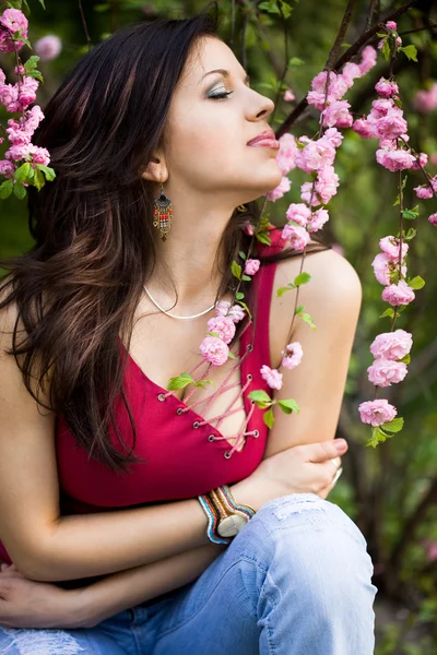 Vrouw in tuin met roze bloemen — Stockfoto