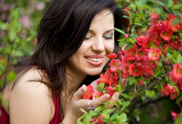 Kobieta w ogrodzie czerwone kwiaty — Zdjęcie stockowe