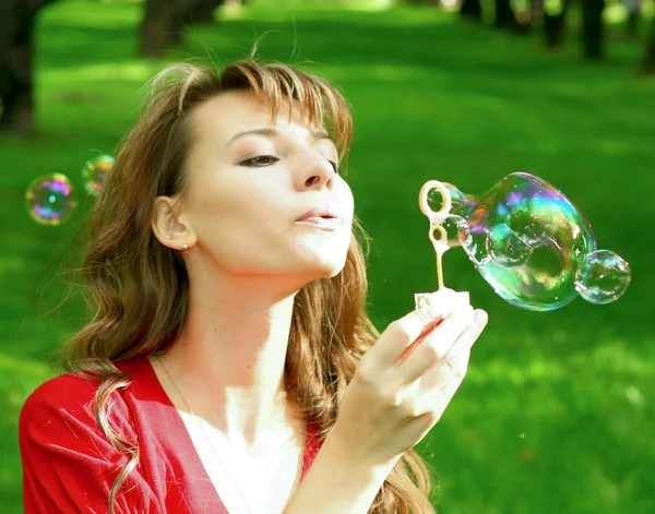 Молодая девушка надувает мыльные пузыри — стоковое фото