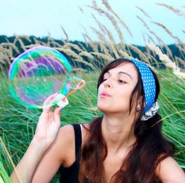 Young girl blowing a big soap bubble clipart