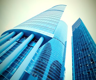 Low angle view to light glass buildings of business center clipart