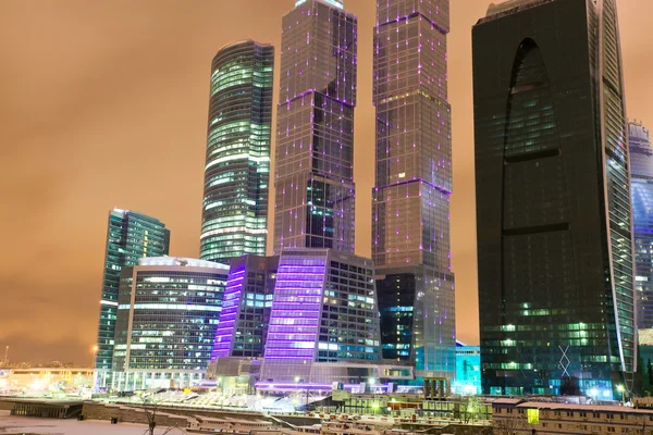Città illuminata piena di moderni edifici in vetro — Foto Stock