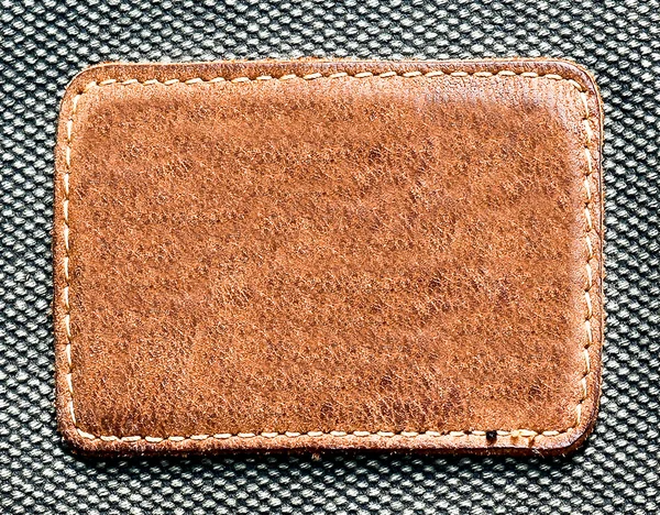 Прямоугольная кожаная этикетка изолирована над текстурой джинсы — стоковое фото