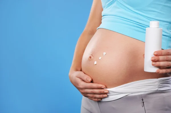 Pregnant woman applying cream to her belly — Stock Photo, Image