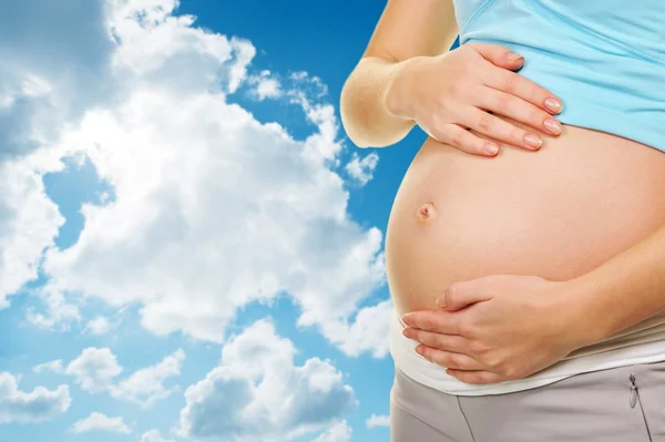 Όμορφη έγκυο κοιλιά πάνω από το μπλε συννεφιασμένο ουρανόレトロなマイクを使って魅力的なブルネットの女性 — Φωτογραφία Αρχείου