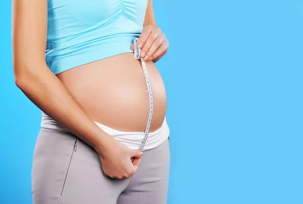 Těhotná žena měří své břicho — Stock fotografie
