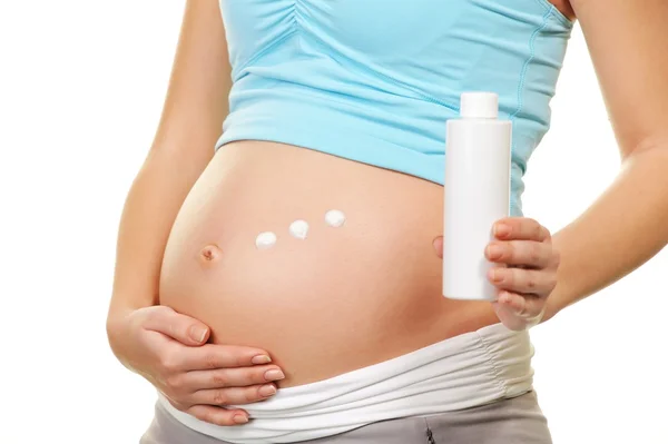 Mujer embarazada aplicando crema en su vientre —  Fotos de Stock