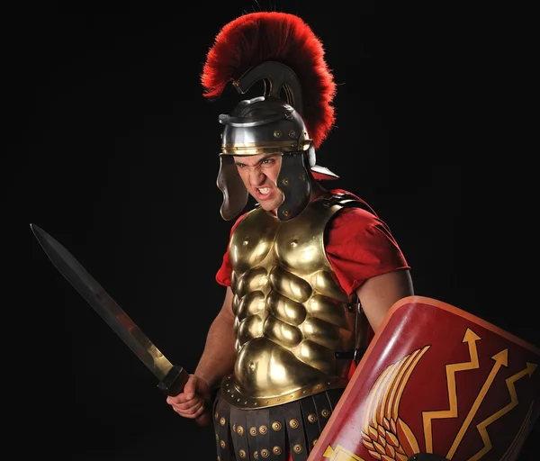Angry legionary soldier with a gladius and shields — Stock Photo, Image
