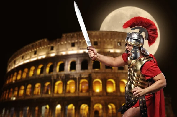 Roman legionary soldier in front of coliseum at night time — Stock Photo, Image