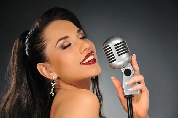 Portret van een mooie brunette met een retro microfoon — Stockfoto