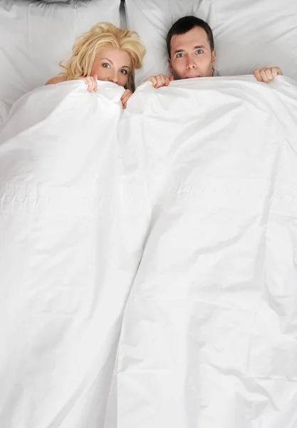 Komik genç bir çift bir yatakta — Stok fotoğraf