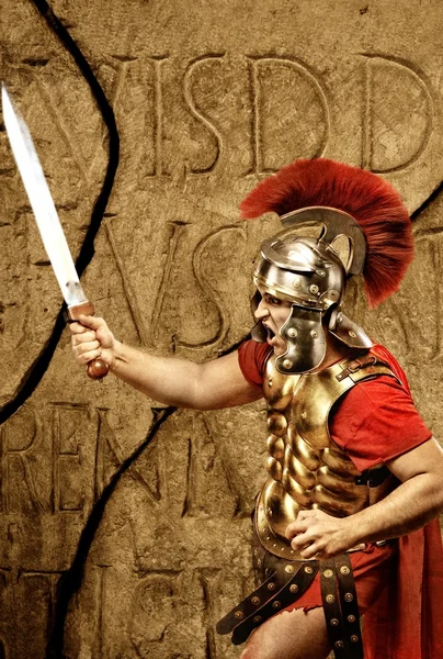 Roman legionary soldier in front of abstract wall — Stock Photo, Image