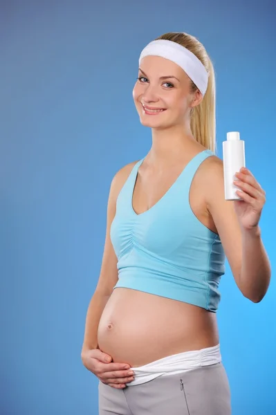Беременная женщина с бутылкой масла — стоковое фото