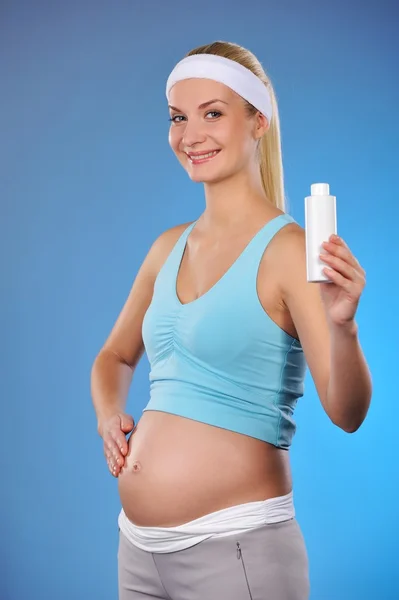 Беременная женщина с бутылкой масла — стоковое фото