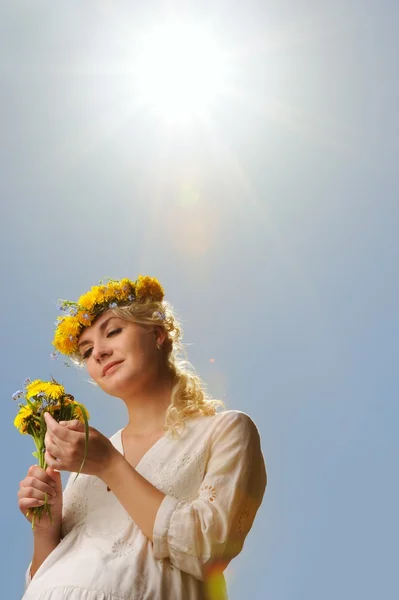 Vacker kvinna med maskros blommor under blå himmel — Stockfoto