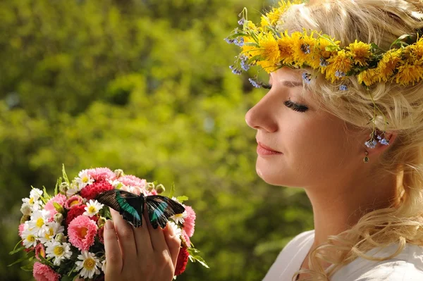 Mooie vrouw met een vlinder en een boeket van bloemen — Stockfoto