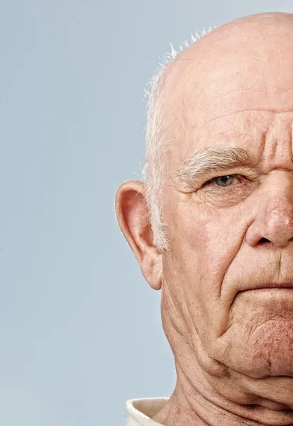 Elderly man's face over blue background — Stock Photo, Image