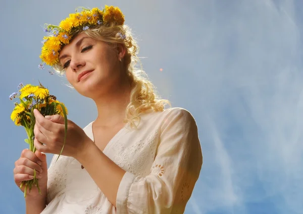 Krásná žena s pampelišky květiny nad modrá obloha — Stock fotografie